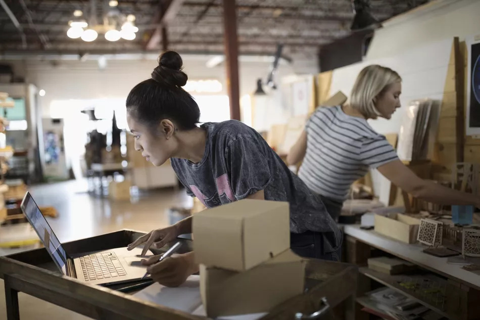 Female Small Business Owner Packaging Merchandise At Laptop In Workshop 769719643 5acb31ac119fa80037ef664c
